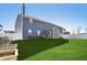 A spacious backyard with lush lawn, white fencing, and a charming blue house with a chimney and a small porch at 1664 Woodside Cir, Franklin, IN 46131