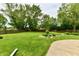 Large backyard with lush green grass, mature trees, tasteful landscaping, and a concrete patio at 18906 Crestview Ct, Westfield, IN 46074