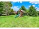 Grassy backyard featuring a wooden play structure complete with a slide and swings at 20170 Starlight Ct, Noblesville, IN 46062