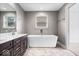 Modern bathroom showcasing a soaking tub, dark vanity with double sinks and a large mirror at 2448 Broadway St, Indianapolis, IN 46205