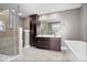 A bathroom featuring a glass shower, dark cabinets, double vanity and a white soaking tub at 2448 Broadway St, Indianapolis, IN 46205