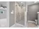 Tiled shower with glass doors in a modern gray bathroom with neutral tile flooring and chrome fixtures at 2448 Broadway St, Indianapolis, IN 46205