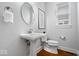 Well-lit half bathroom with a pedestal sink, round mirror, and modern fixtures at 2448 Broadway St, Indianapolis, IN 46205