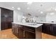 Kitchen island with stainless steel sink, quartz countertops, and dark cabinets, opens to living area at 2448 Broadway St, Indianapolis, IN 46205