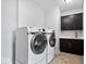 Convenient laundry room with front load washer and dryer, sink and dark cabinets at 2448 Broadway St, Indianapolis, IN 46205