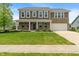Two-story home boasts manicured lawn, brick accents, covered porch, and an attached two car garage at 2626 Solidago Dr, Plainfield, IN 46168