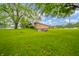 Lush backyard with a brick home, mature trees, and a storage shed at 2900 Helms Rd, Anderson, IN 46016