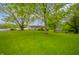 Expansive backyard featuring lush green grass and mature trees providing ample shade at 2900 Helms Rd, Anderson, IN 46016