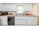 Traditional kitchen with white cabinets, black appliances, and a double basin sink under a window at 2900 Helms Rd, Anderson, IN 46016