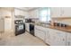 Traditional kitchen with white cabinets, black appliances, and a double basin sink under a window at 2900 Helms Rd, Anderson, IN 46016
