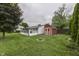 Scenic view of the backyard, showcasing the red shed, enclosed sunroom, fire pit, and lush green lawn at 454 E Broadway St, Greenwood, IN 46143