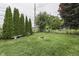 Well-maintained backyard with a circular fire pit, evergreen trees, and a bench offering a serene outdoor space at 454 E Broadway St, Greenwood, IN 46143