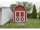 A quaint red shed with white trim and double doors, set on a well-kept lawn, perfect for storage at 454 E Broadway St, Greenwood, IN 46143