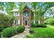 Charming two-story brick home with lush landscaping, bright green lawn, and a welcoming red front door at 50 Charing Cross Rd, Indianapolis, IN 46217