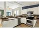 A well-lit kitchen featuring white cabinets, stainless steel appliances, and a stylish backsplash and open access to the dining room at 514 Dorman St, Indianapolis, IN 46202