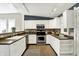 A well-lit kitchen featuring white cabinets, stainless steel appliances, and a stylish backsplash and open access to the dining room at 514 Dorman St, Indianapolis, IN 46202