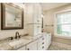A luxurious bathroom showcasing granite counters, dual sinks, white cabinets and modern fixtures complemented by a patterned tile floor at 5254 N Park Ave, Indianapolis, IN 46220