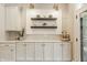 Butler's pantry area featuring white cabinets, floating shelves, decorative accents, and views to the outside at 5254 N Park Ave, Indianapolis, IN 46220