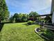 Expansive backyard featuring lush green lawn, mature trees, iron fence, and stylish pergola with outdoor seating at 5347 Sampson Dr, Indianapolis, IN 46237
