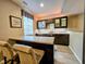 An elegant wet bar features dark wood cabinets with glass doors, granite countertops, and stylish barstool seating at 5347 Sampson Dr, Indianapolis, IN 46237