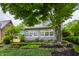 Charming home exterior featuring a sunroom, tiered landscaping, and mature trees at 5430 N Washington Blvd, Indianapolis, IN 46220