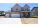 Two-story home featuring a three-car garage, gray siding, brick accents, and a covered front porch at 5517 Sienna Ct, Brownsburg, IN 46112