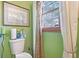 A bathroom featuring green walls, a white toilet, and natural light at 6210 Mckinley Ct, Indianapolis, IN 46220