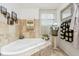 Elegant bathroom with a soaking tub, travertine tile, and natural light from the window at 6210 Mckinley Ct, Indianapolis, IN 46220