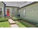 Exterior view of a home with green siding, a bright red front door, and lovely landscaping at 6210 Mckinley Ct, Indianapolis, IN 46220