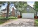 Exterior view of a charming green home with white garage door, red door and mature trees at 6210 Mckinley Ct, Indianapolis, IN 46220
