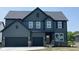 Stunning two-story home featuring a three car garage, covered porch and a dark grey exterior at 6418 Springtide Ct, Plainfield, IN 46168