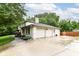 Exterior view of a white house with a large driveway and attached garage surrounded by lush greenery at 6530 Lowanna Way, Indianapolis, IN 46220
