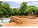 Expansive wooden deck with a swimming pool, outdoor seating, and lush green trees in the background at 6530 Lowanna Way, Indianapolis, IN 46220
