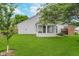 View of a home's backyard with lush green grass, brick patio, and bright sunroom at 6789 Passage Cir, Indianapolis, IN 46250