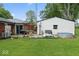 Spacious backyard with a wooden deck, manicured lawn, detached white-sided garage and mature trees at 679 Bark Dr, Anderson, IN 46011