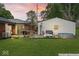 Backyard at dusk with a furnished wooden deck, green lawn, detached white garage, and mature trees at 679 Bark Dr, Anderson, IN 46011