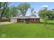 Well-kept red brick home featuring a metal roof, attached garage, and lush green lawn at 679 Bark Dr, Anderson, IN 46011