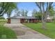 Charming red brick home with a metal roof, green door, and a well-maintained front yard at 679 Bark Dr, Anderson, IN 46011