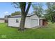 Detached garage with white siding, featuring a large tree and freshly cut green lawn, perfect for storage at 679 Bark Dr, Anderson, IN 46011