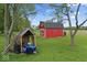 Exterior view of the red barn and a wood shed in the expansive backyard of the property at 679 Bark Dr, Anderson, IN 46011