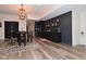 Basement wet bar features dark cabinetry, floating shelves, stainless steel refrigerator, and pub table with seating at 7070 Dean Rd, Indianapolis, IN 46220