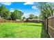 Expansive backyard with lush green grass, wooden fence, mature trees, and a clear blue sky at 7437 Lorene Ct, Indianapolis, IN 46237