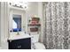 Cozy bathroom featuring a vanity with storage, mirrored cabinet, toilet with shelving, and patterned shower curtain at 7437 Lorene Ct, Indianapolis, IN 46237