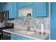 Kitchen featuring blue cabinets, patterned backsplash, modern appliances, and ample counter space at 8 W Jackson St, Knightstown, IN 46148