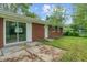 Red brick house exterior with a sliding glass door, white trim, and a spacious backyard with a green lawn at 8109 E Penway St, Indianapolis, IN 46226