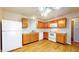 Well-lit kitchen with laminate floors, wood cabinets, white appliances, and a stainless steel sink at 8121 Sand Ridge Cir, Indianapolis, IN 46237