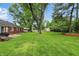 Spacious backyard featuring mature trees, lawn, and brick house at 8752 Washington Blvd E Dr, Indianapolis, IN 46240