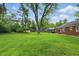 Large backyard with mature trees, lawn, and brick exterior of house at 8752 Washington Blvd E Dr, Indianapolis, IN 46240