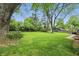 Large backyard with mature trees, level lawn, and exterior storage at 8752 Washington Blvd E Dr, Indianapolis, IN 46240