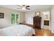 Sunlit bedroom showcasing wood floors, a ceiling fan, closet, and an ensuite bathroom, all in neutral tones at 8752 Washington Blvd E Dr, Indianapolis, IN 46240